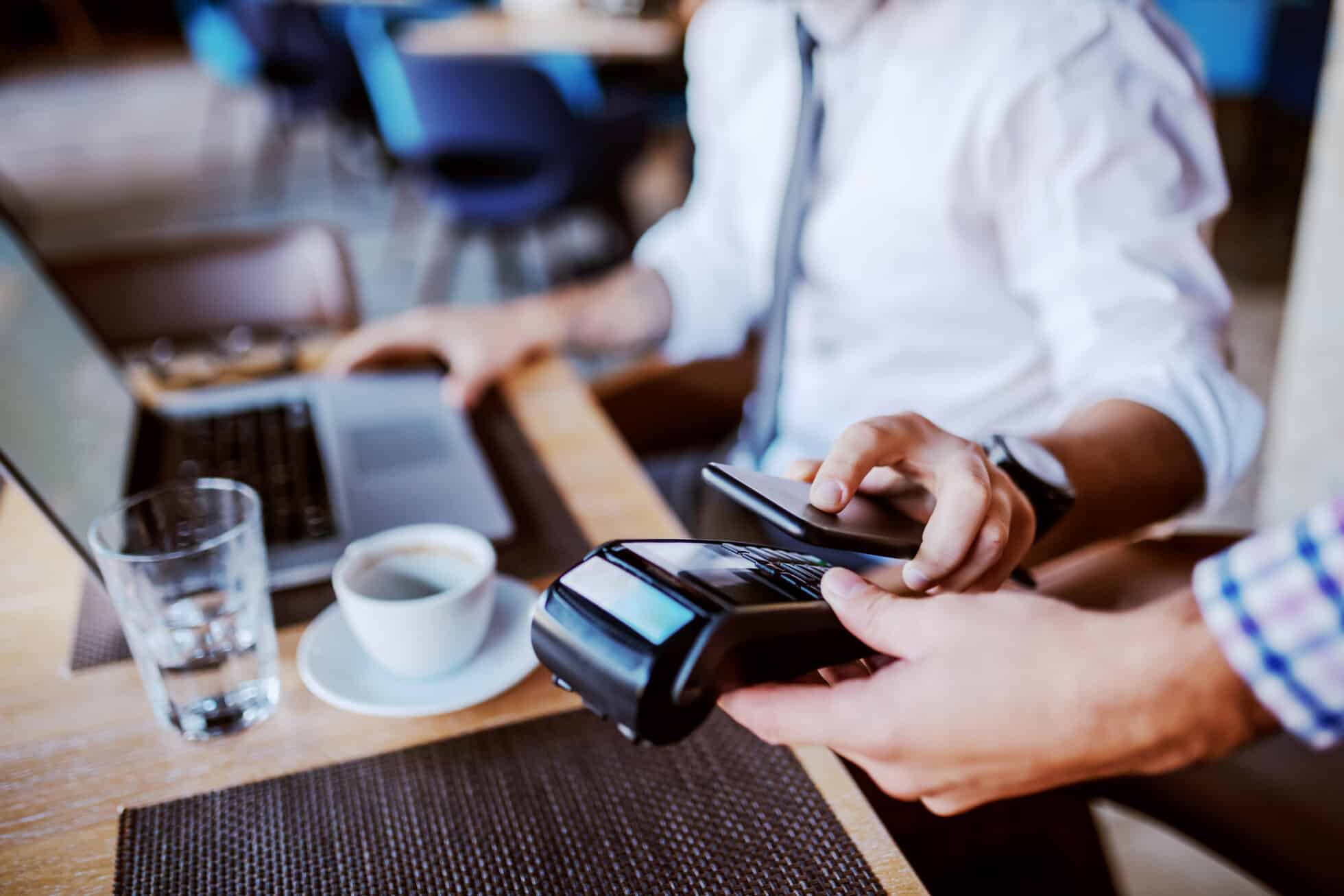 Person using contactless payment with their phone while using a computer